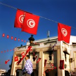 Tunisia, Tunis
A man walks underneath national flags with a government building in the background, burned during the revolution.