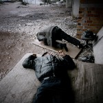 Greece, Patras. Arif lies down on the ground next to the building where he is squatting whilst Haroon prays.