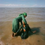 Mozambique, Maputo. An adherant from a Zion church washing another woman during a purification ceremony on a beach.